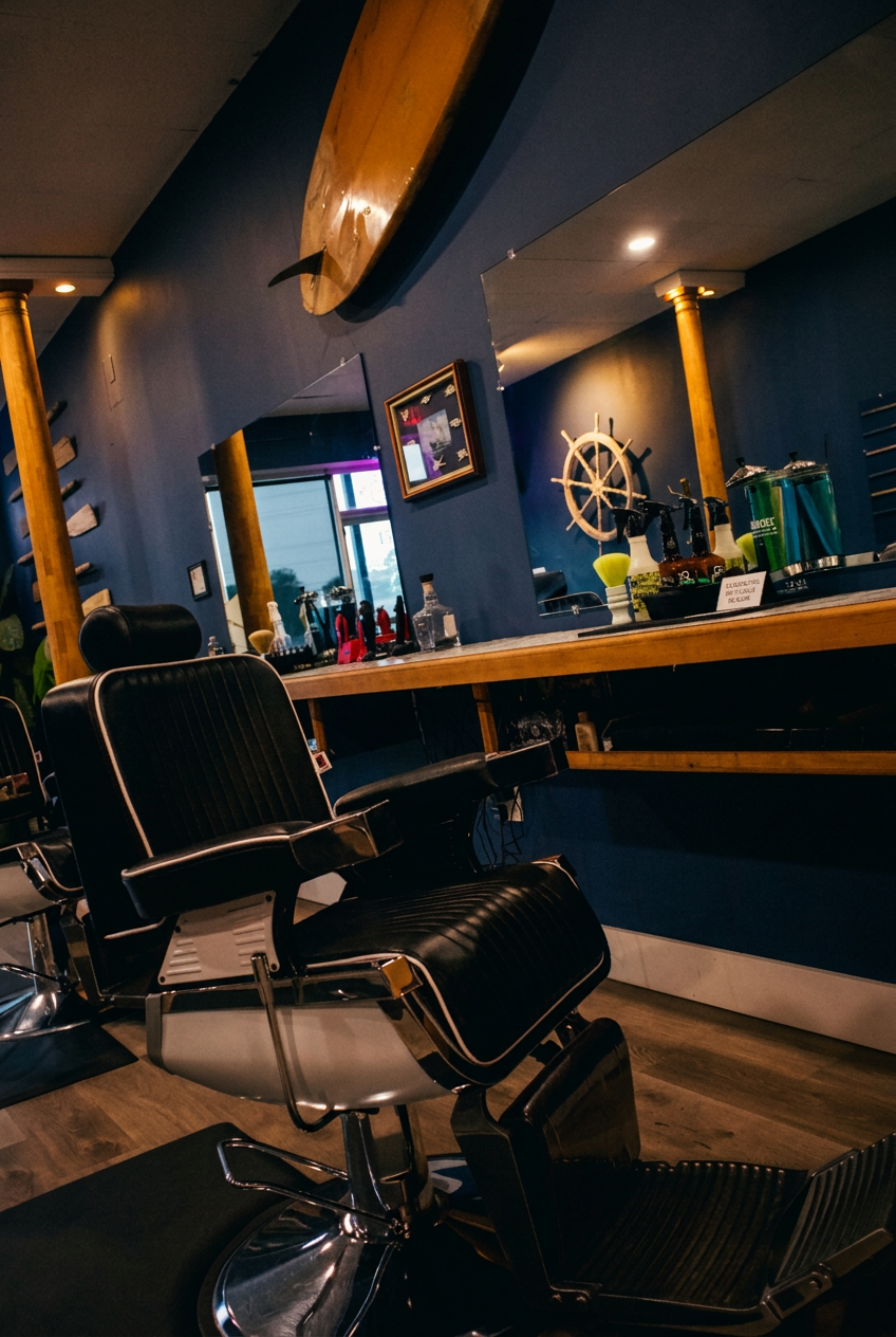 Coastal station — black leather barber chair, surfboard and ship wheel decor